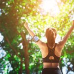 Young woman engaged in sports while listening to music. Take a resting and drinking water.