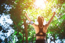 Young woman engaged in sports while listening to music. Take a resting and drinking water.