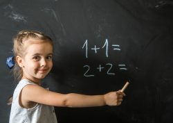 Cute girl schoolgirl near blackboard with chalk in hand,the concept of education and school life
