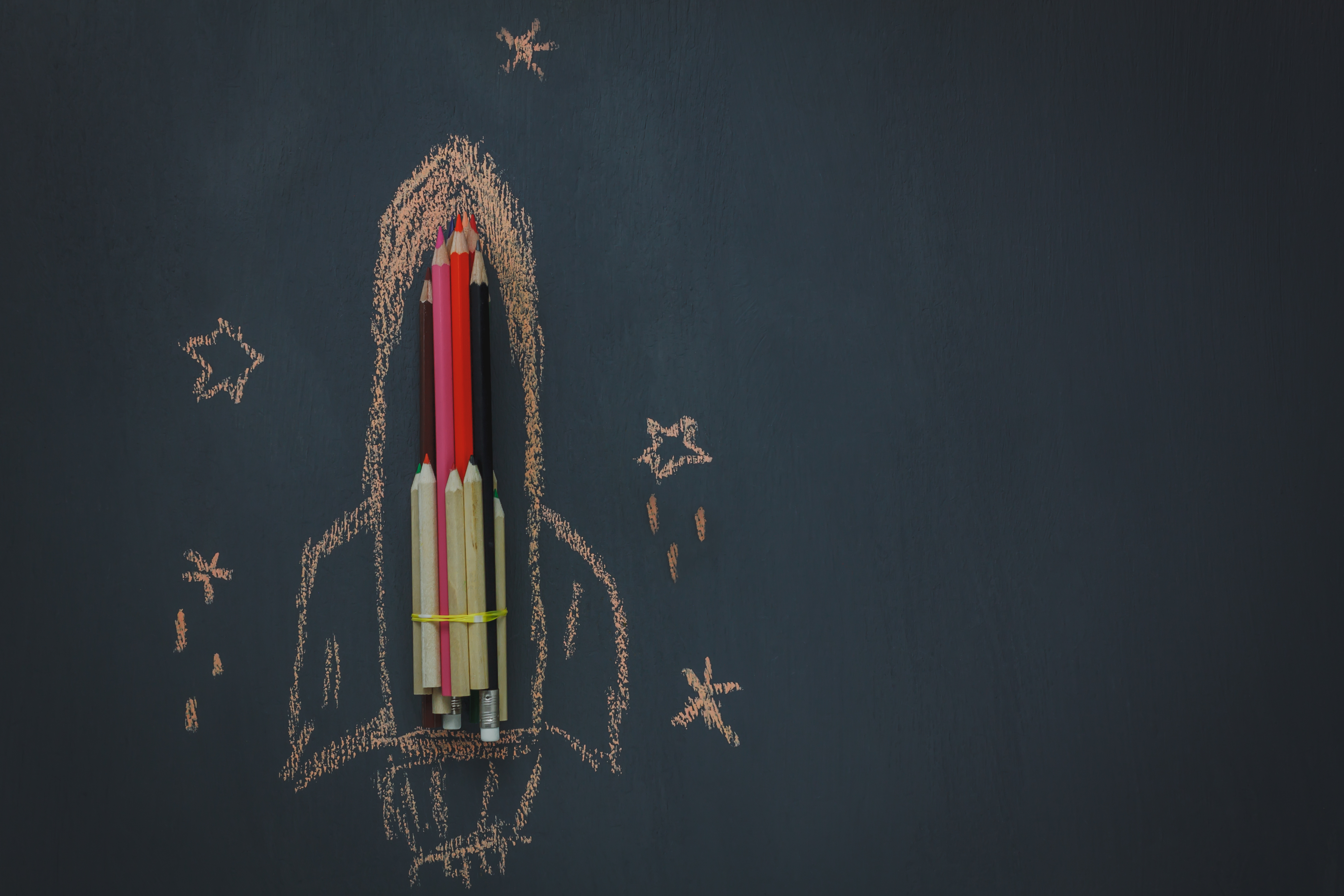Top view Back to school or business start up background.The rocket create by pencil and drawing by chalk board with around star on blackboard.copy space.above view.flat lay.