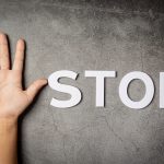 word "stop" with child's hand on dark background